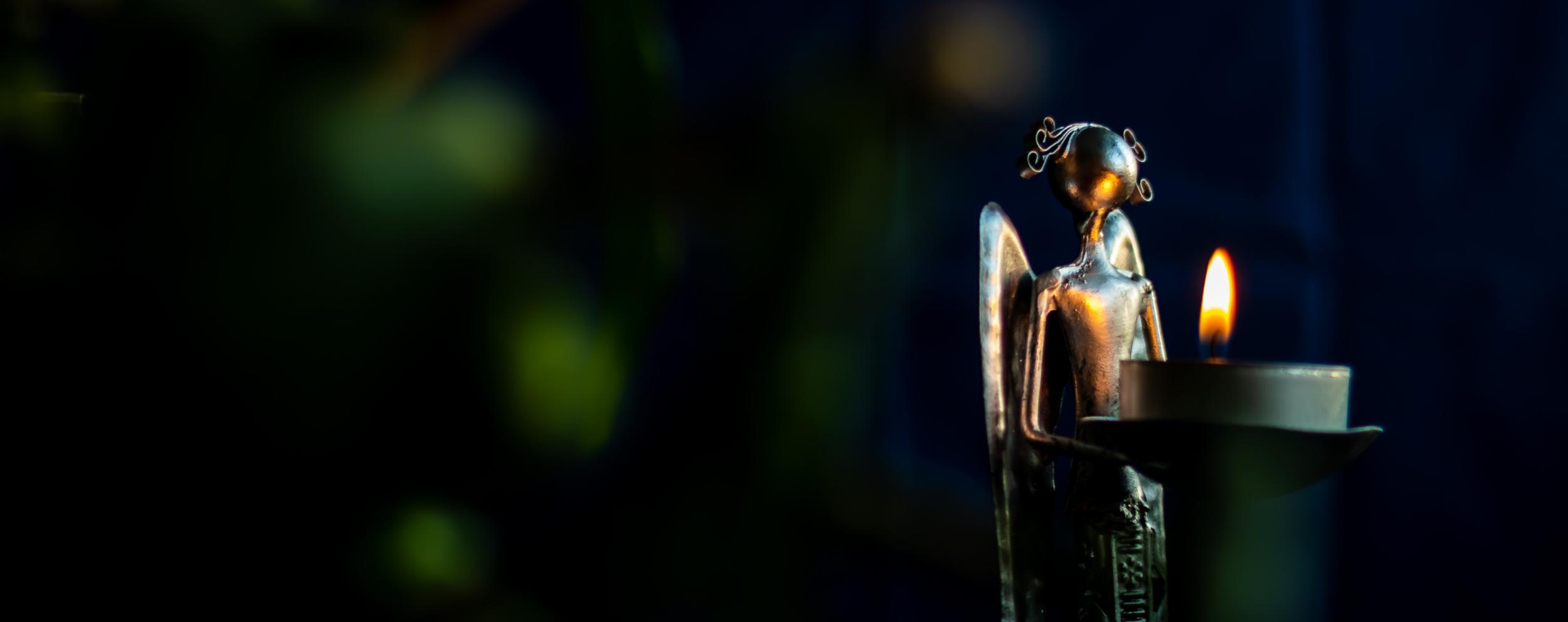 Bild von einem Engel aus Metall mit einem Teelichthalter und einer brennenden Kerze