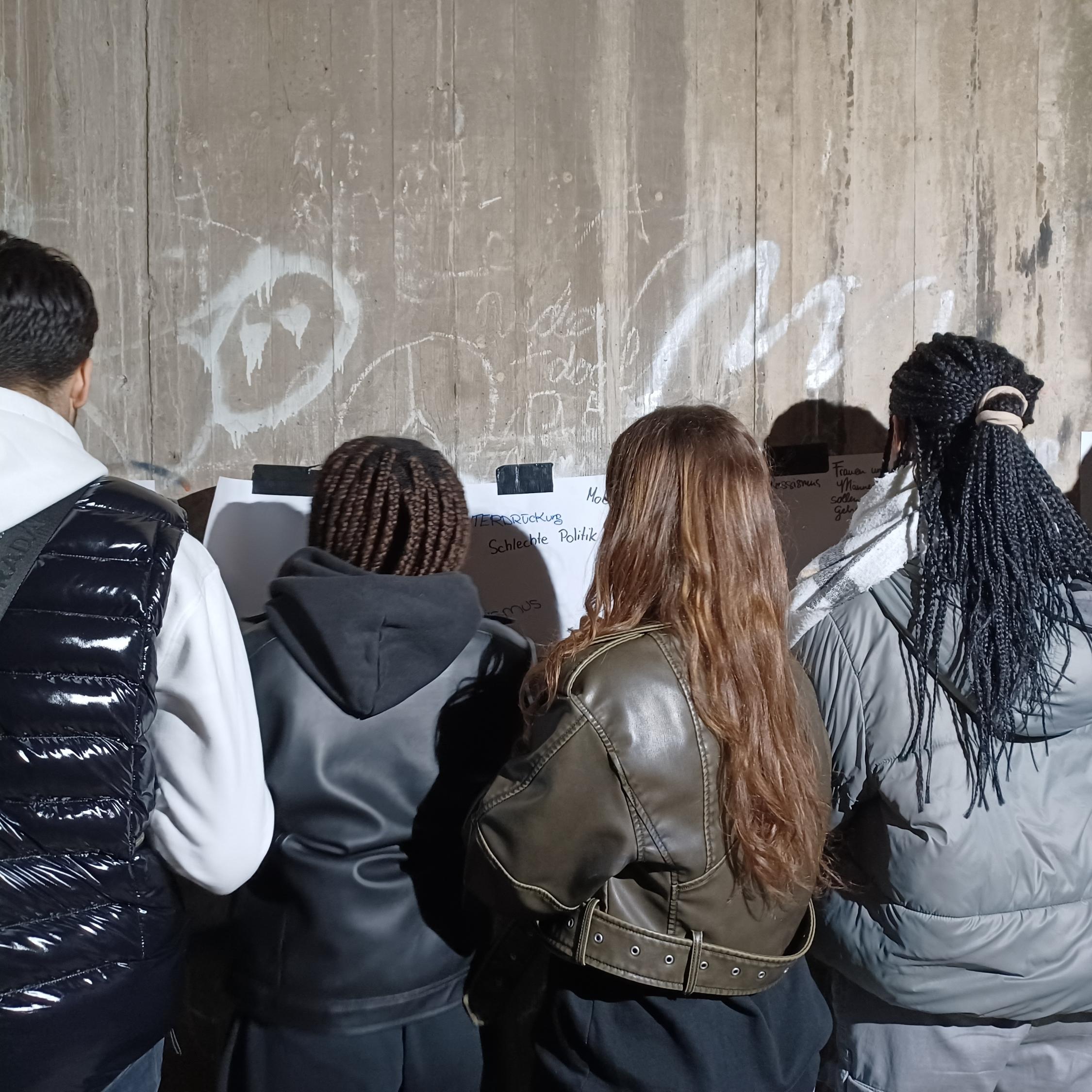 Foto zeigt Jugendliche vor einer Wand Bilder am malen