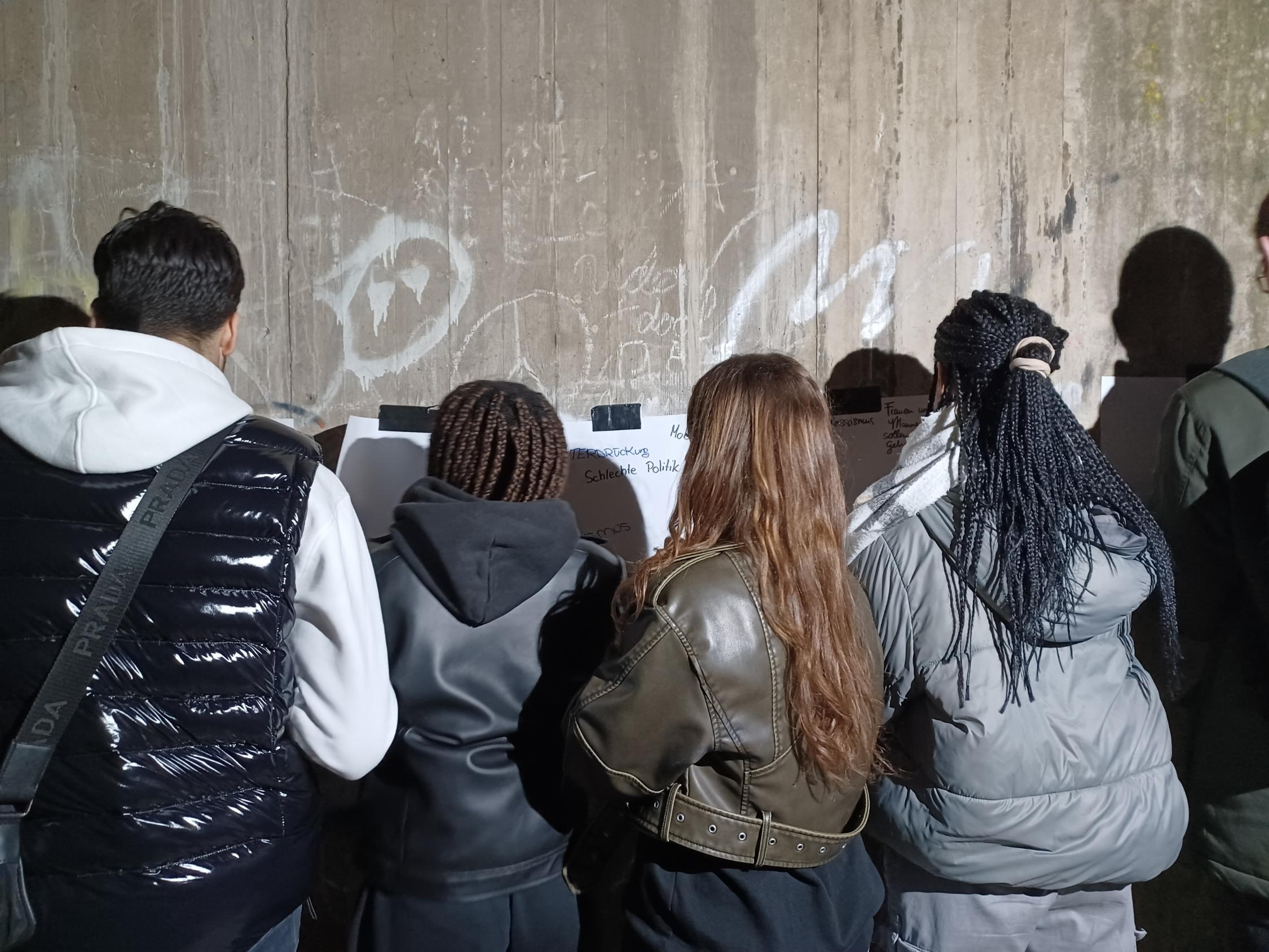 Foto zeigt Jugendliche vor einer Wand Bilder am malen