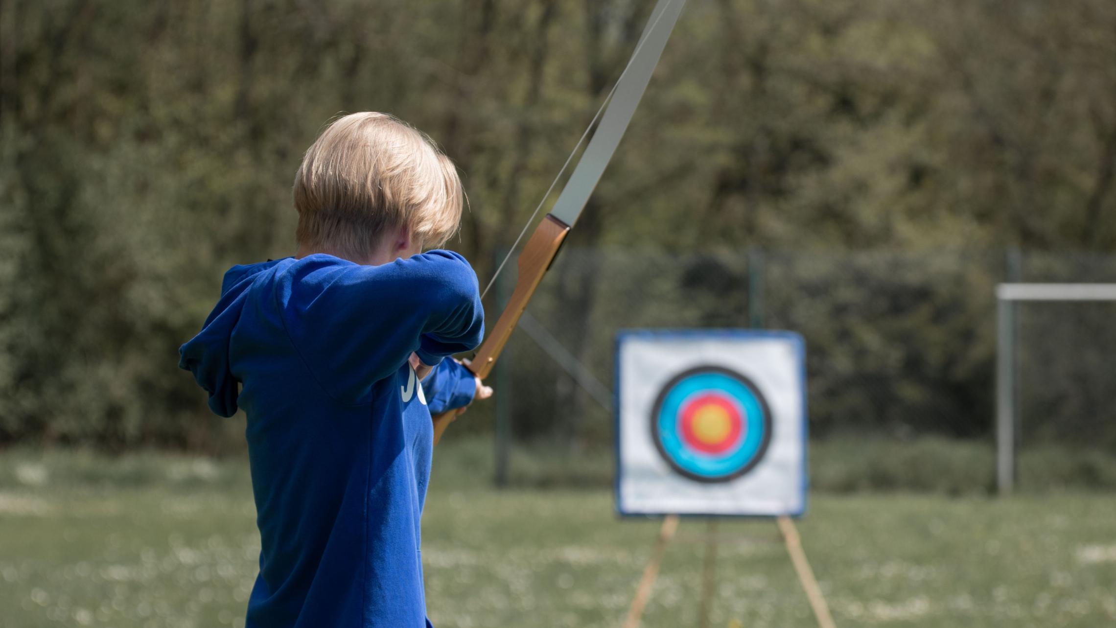 Ein Foto von einem jungen Mann der Bogenschießen übt.